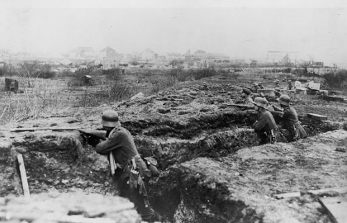 Men shoot from a trench